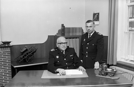 851252 Portret van scheidend brandweercommandant J. Das (zittend), met rechts zijn opvolger J. 't Lam, op zijn ...